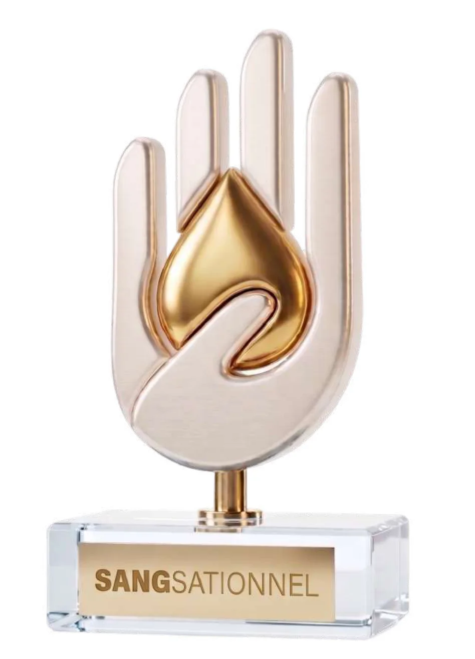 Maquette du Trophée Sangsationnel : une main dorée traversée d'une goutte, sur un socle en cristal